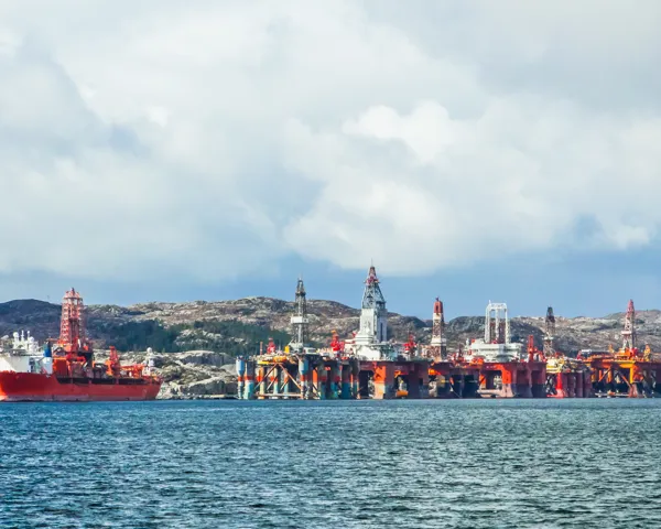 Illustrasjonsbilde av flere oljeplatform og en stor båt nær kysten