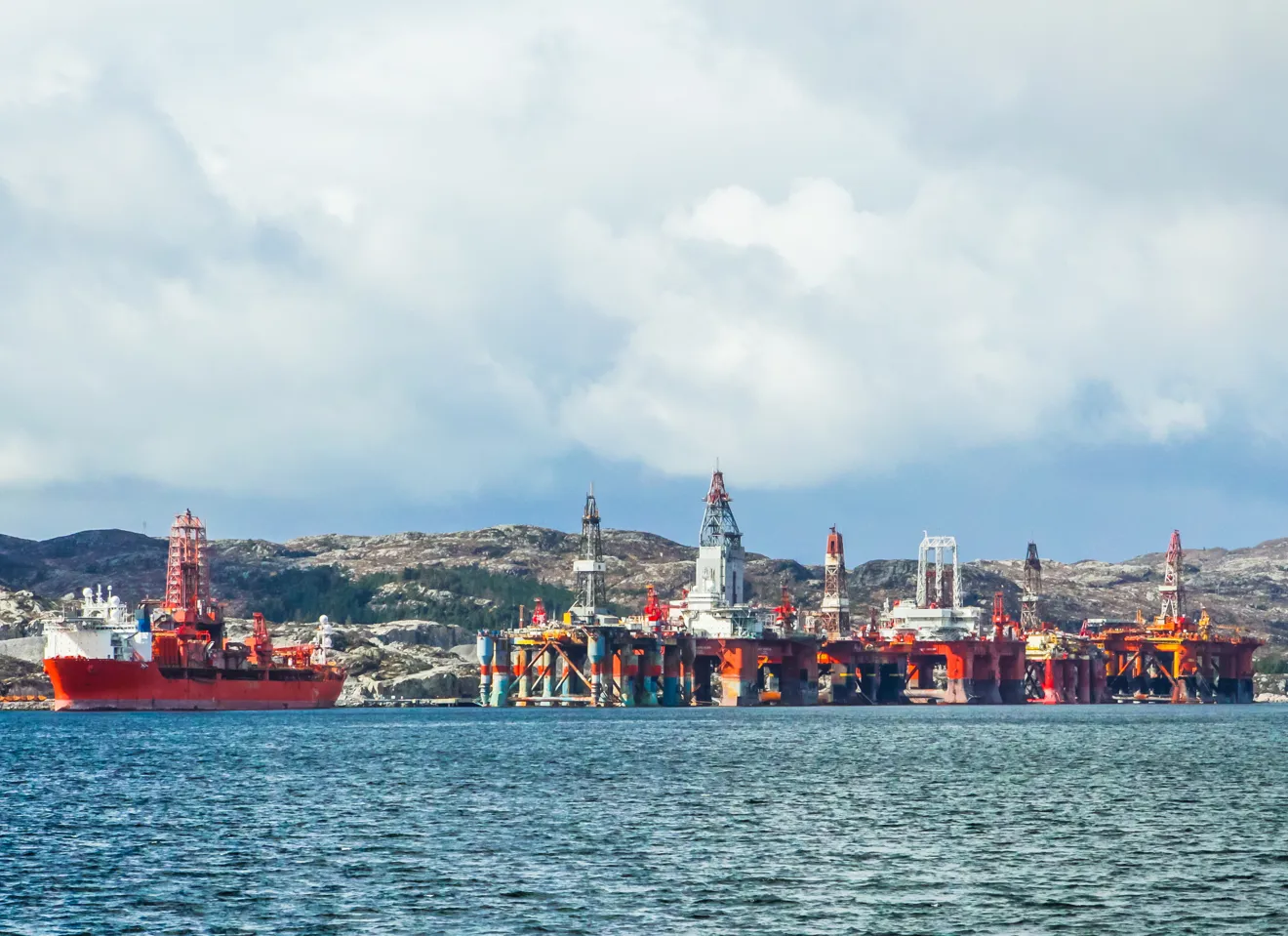 Illustrasjonsbilde av flere oljeplatform og en stor båt nær kysten