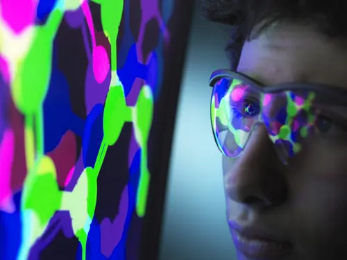 Illustrasjonsbilde av en mann med briller som reflekterer lys fra en TV skjerm