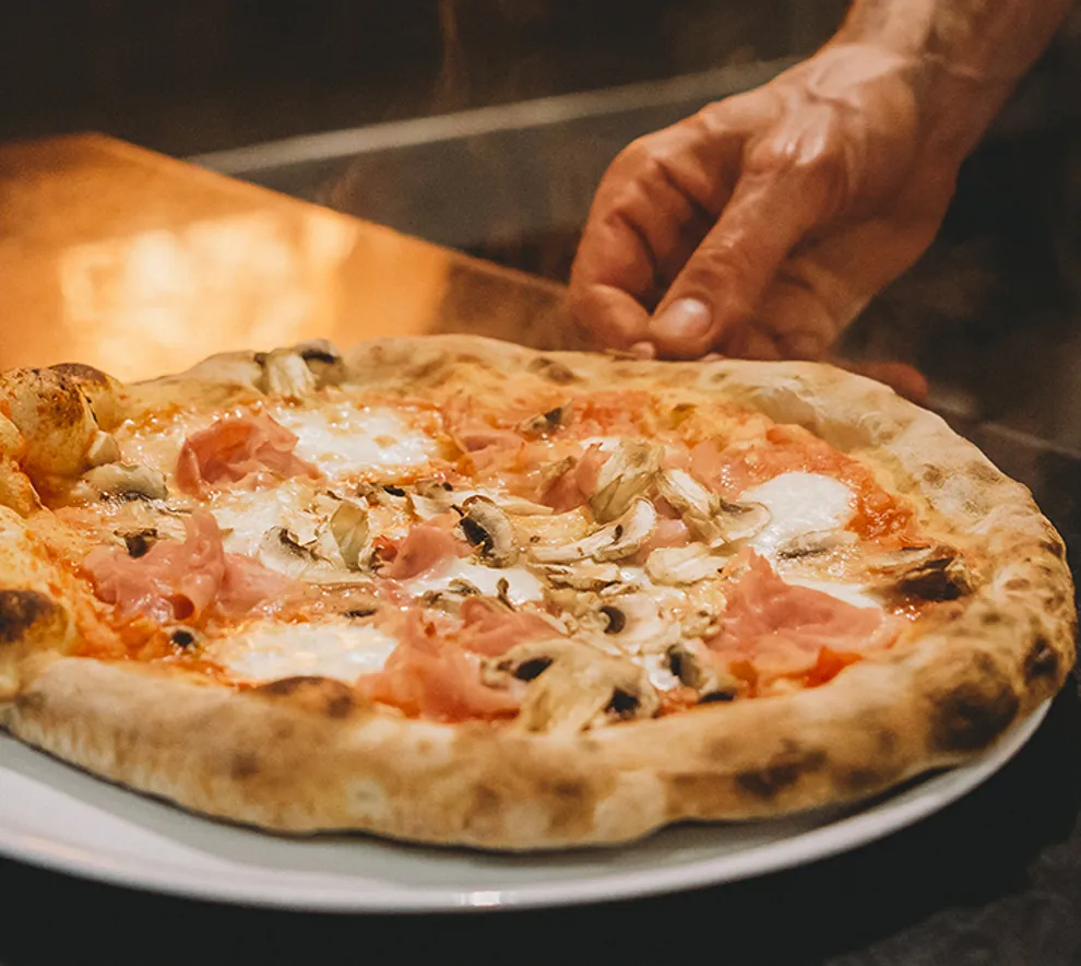 Italiensk pizza lagt på tallerken klar til servering