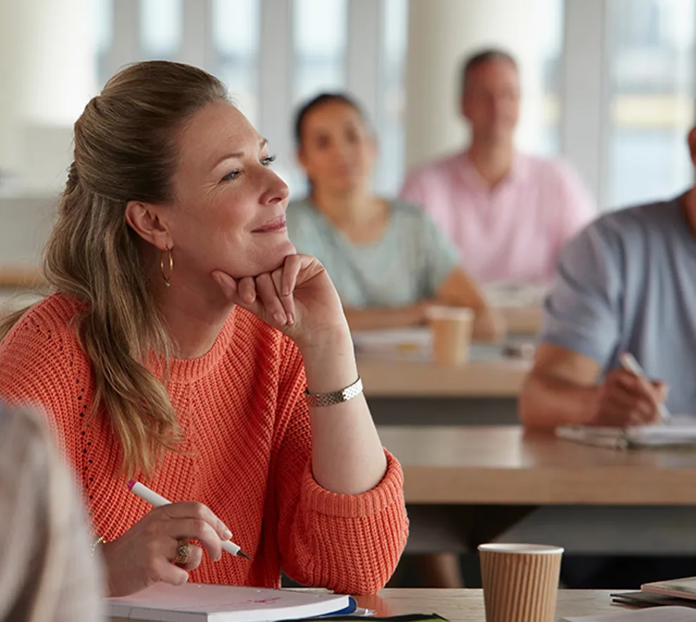 Kvinne som har hånden under haken og gjør notater