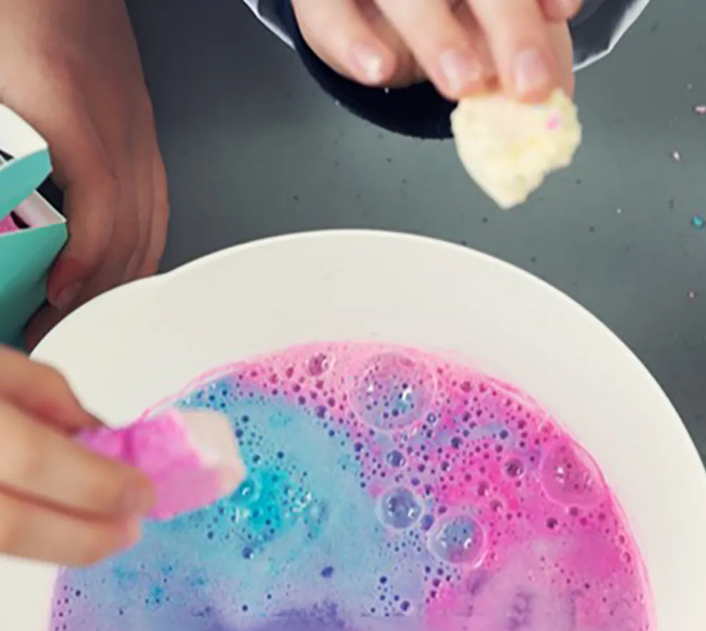 Barnehender som eksperimenterer med farger og vann
