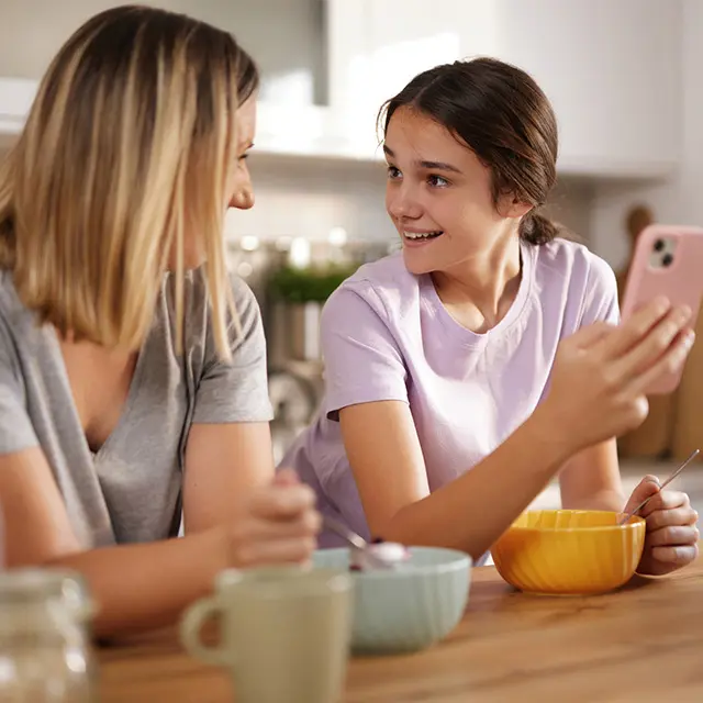 Mor som snakker med datter ved frokostbordet