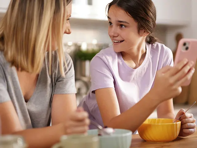 Mor som snakker med datter ved frokostbordet