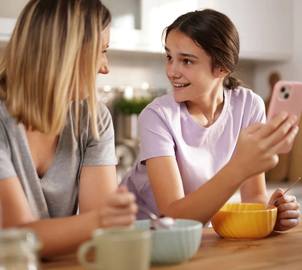 Mor som snakker med datter ved frokostbordet