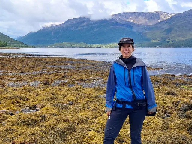 Kvinne på strand med masse tang