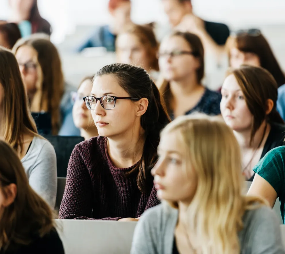 Universitetsstudenter som sitter på forelesning. En gruppe unge kvinner som sitter på rekker