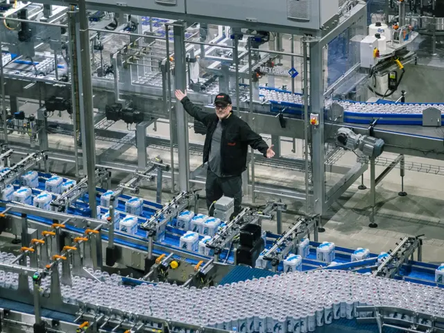 Mann blant samlebånd med ølbokser