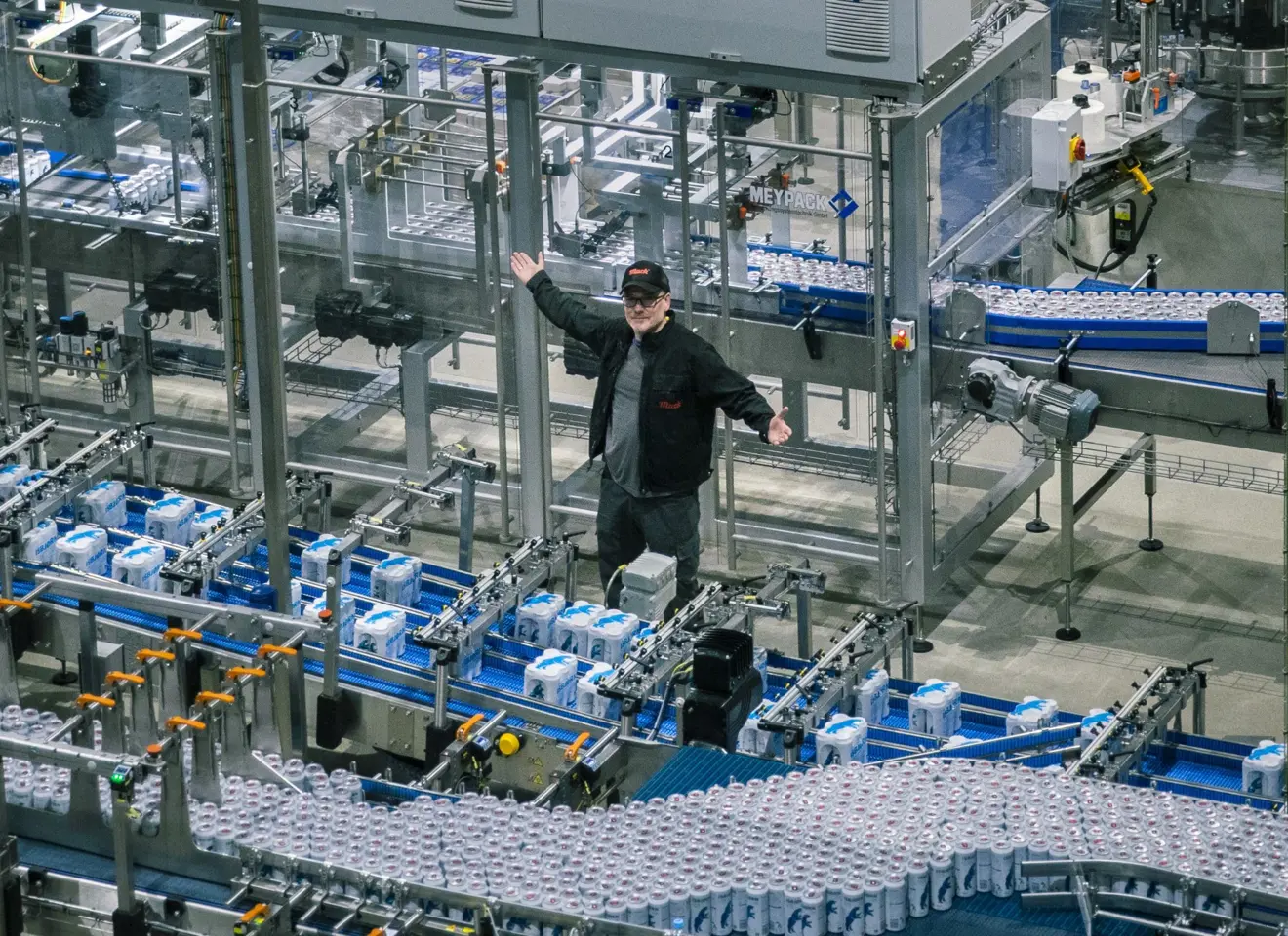 Mann blant samlebånd med ølbokser