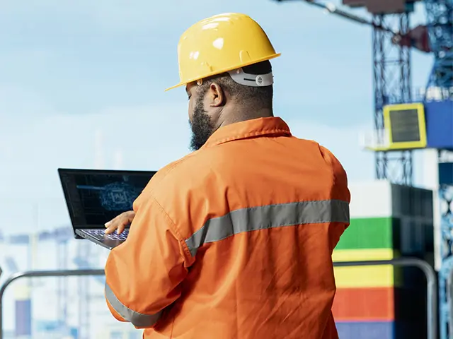 En mannlig offshore-arbeider som sjekker data på PC-en