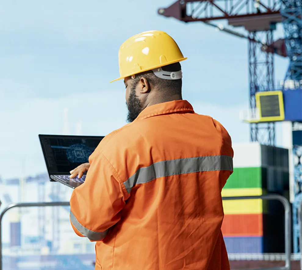 En mannlig offshore-arbeider som sjekker data på PC-en