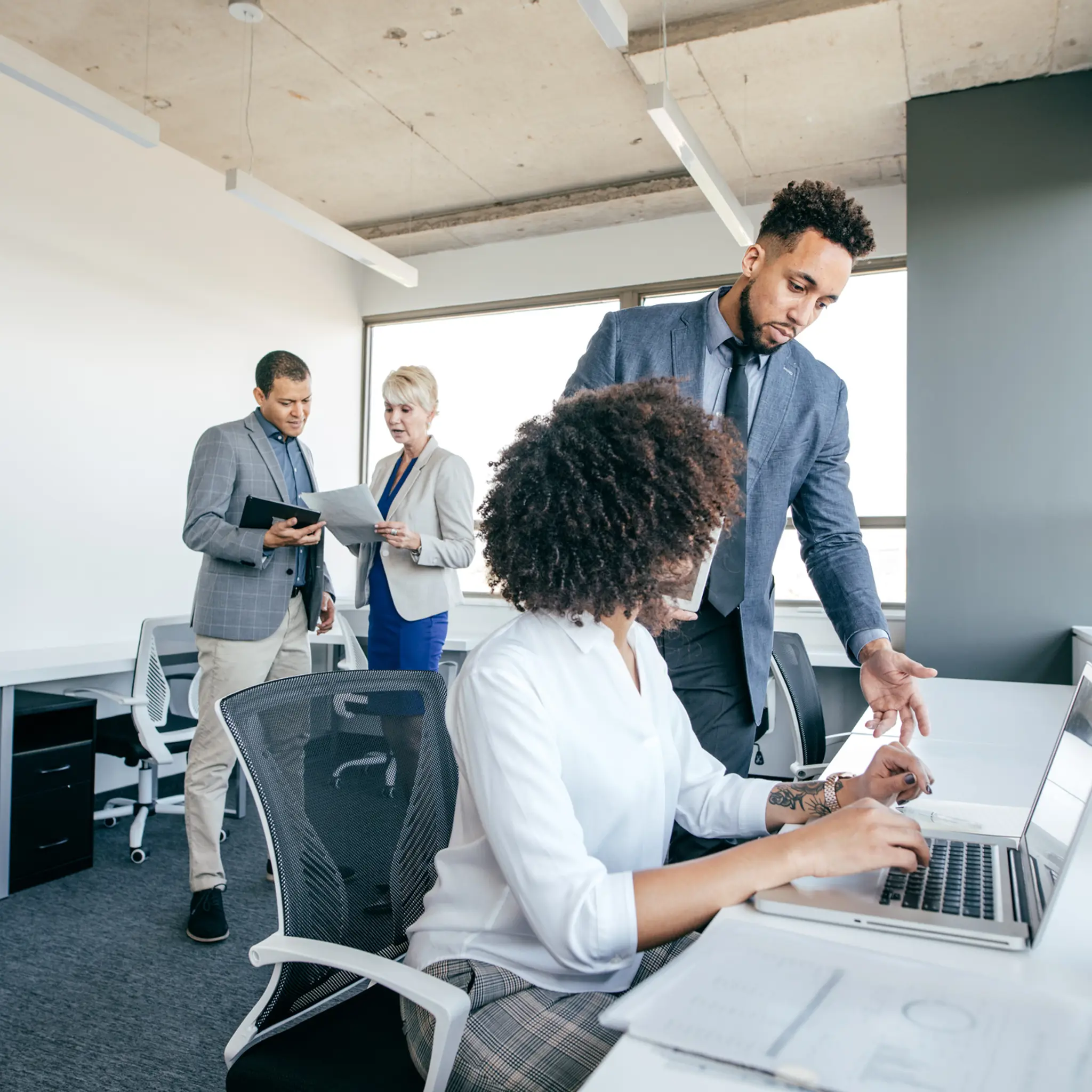 Illustrasjonsbilde av to menn og to kvinner stående og sittende i kontorlandskap