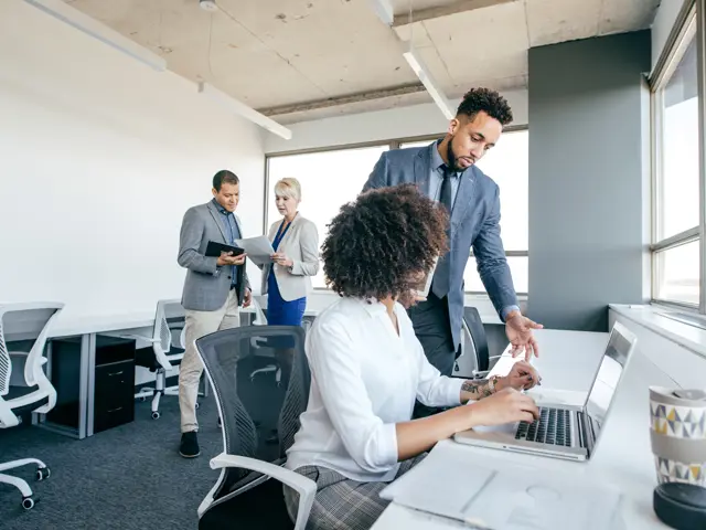 Illustrasjonsbilde av to menn og to kvinner stående og sittende i kontorlandskap