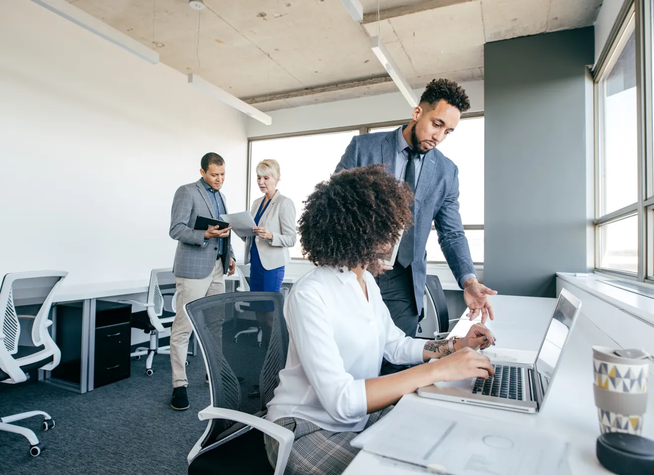 Illustrasjonsbilde av to menn og to kvinner stående og sittende i kontorlandskap