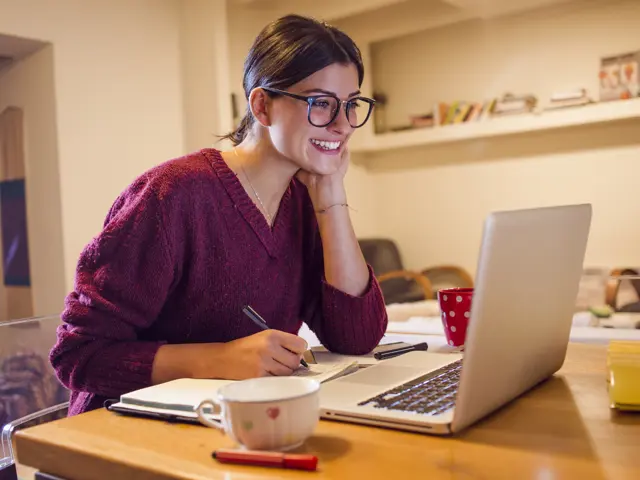 Bilde av person som smiler foran en bærbar PC