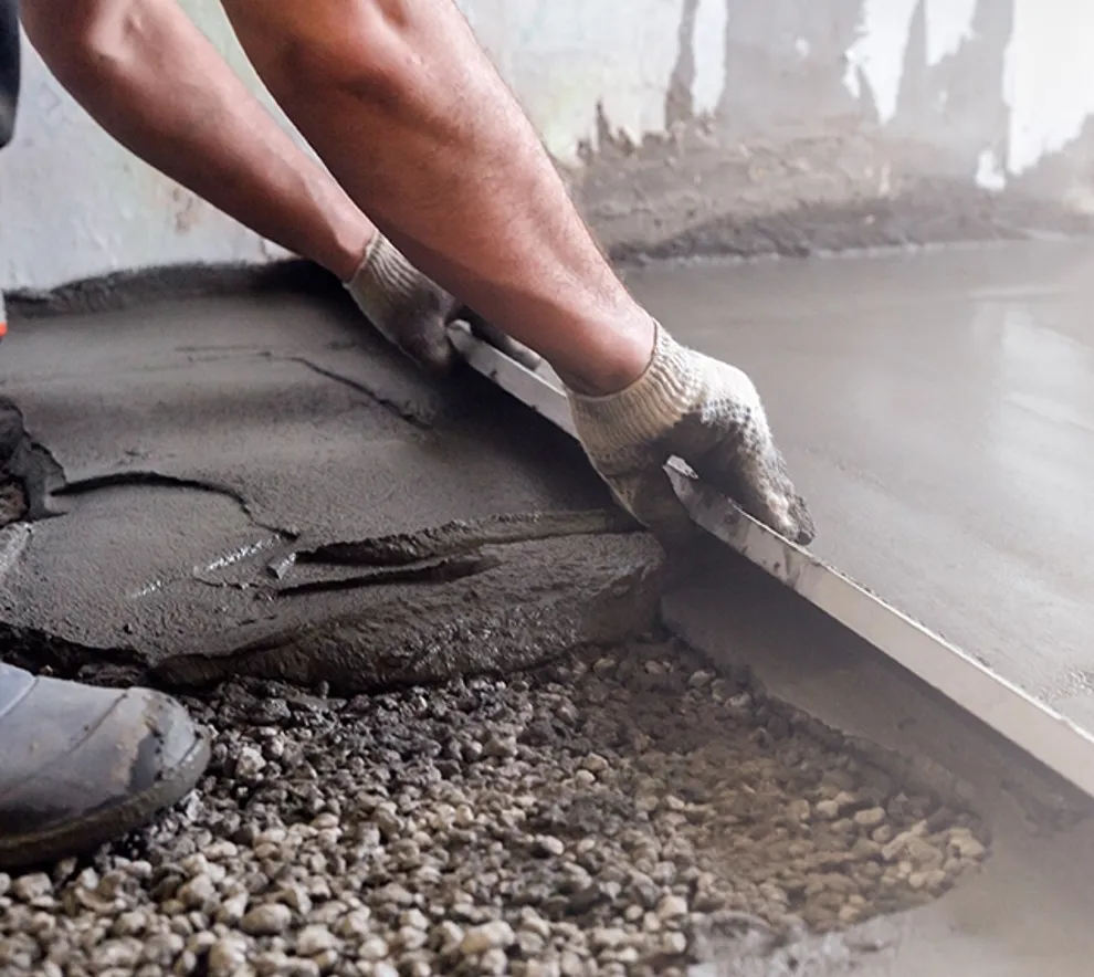 Betongarbeider som drar betong utover gulvflaten så det blir jevnt