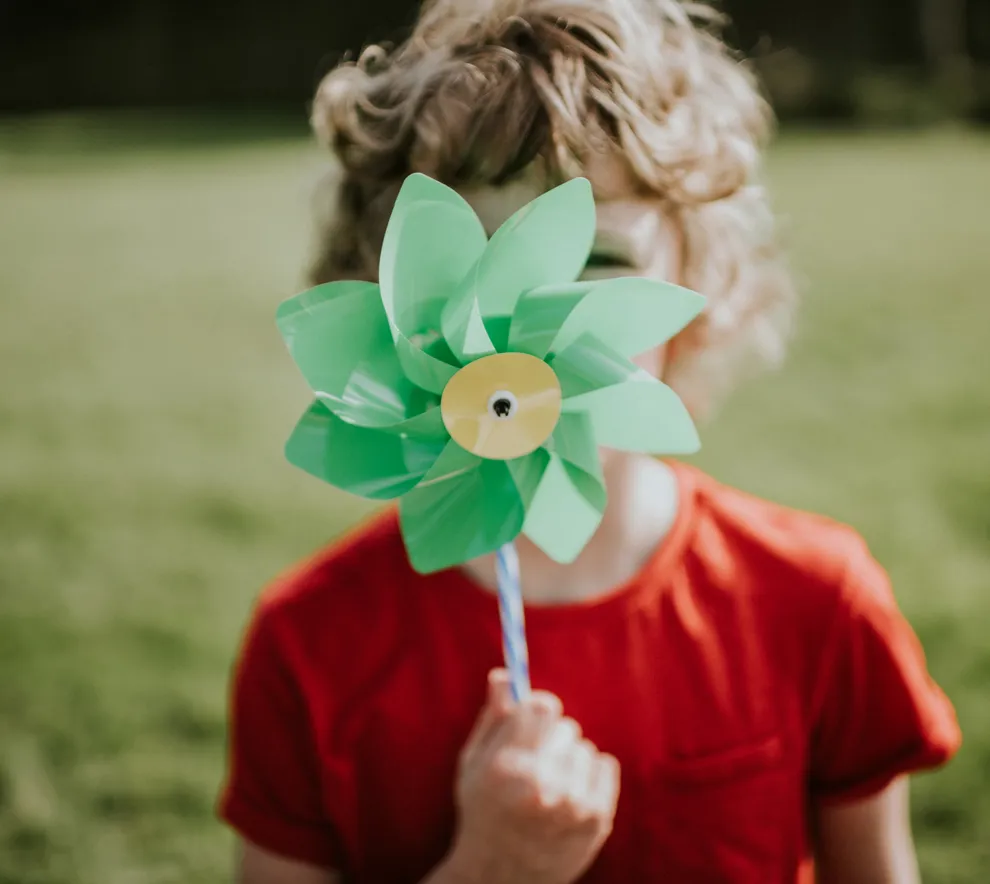 Profilbilde av et barn med en leke-vindmølle foran fjeset