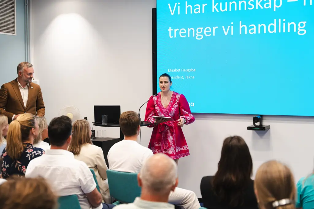 President Elisabet Haugsbø under Teknas arrangement Dette er løsningene på realfagskrisen i Arendal, Haugsbø prater til en sal med publikum, foran en skjerm