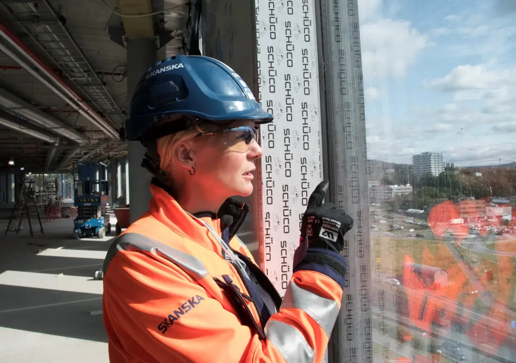 Karin Synnøve Lund i verneutstyr peker ut av vindu