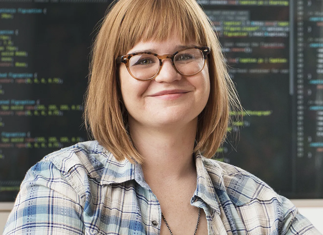 Kvinne smiler, programmerings-kode i bakgrunnen