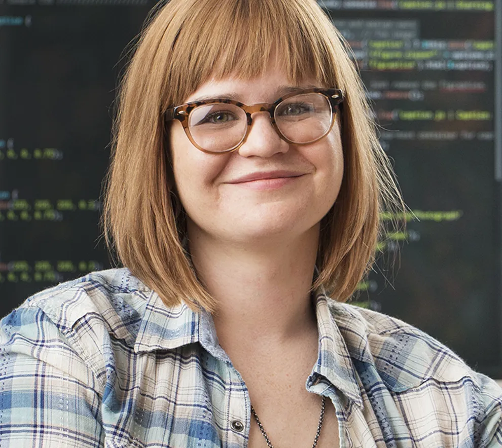 Kvinne smiler, programmerings-kode i bakgrunnen