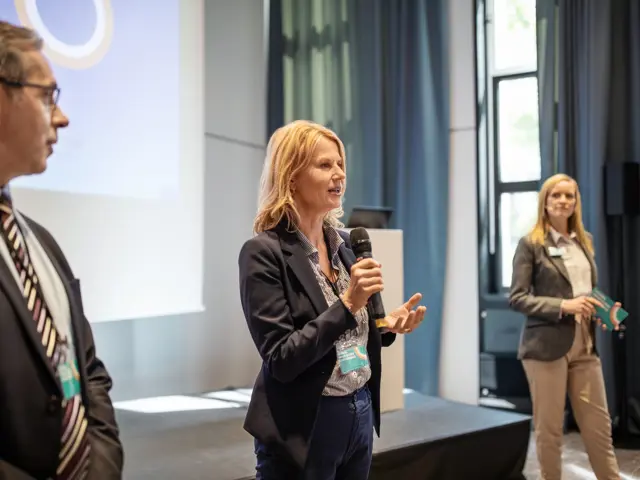 Tre personer på scene prøver seg på å holde taler