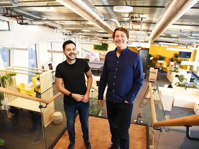 Martin Skarbø Sangolt og Christian Mikalsen står i toppen av en trapp i et kontorlokale med gule vegger