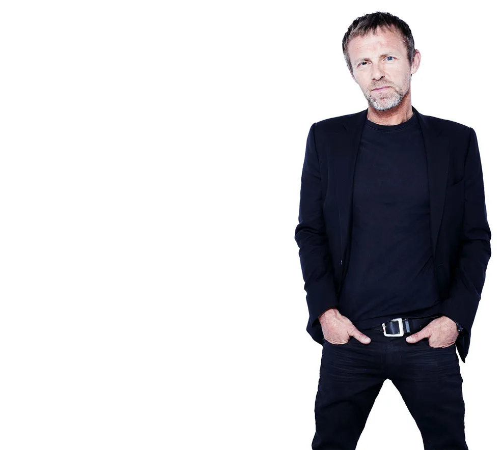 Jo Nesbø i svart dress ser i kamera.