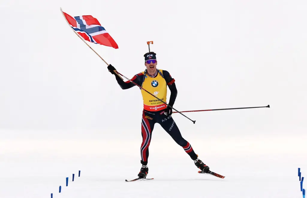 Skiskytter i gul ledertrøye og norsk flagg