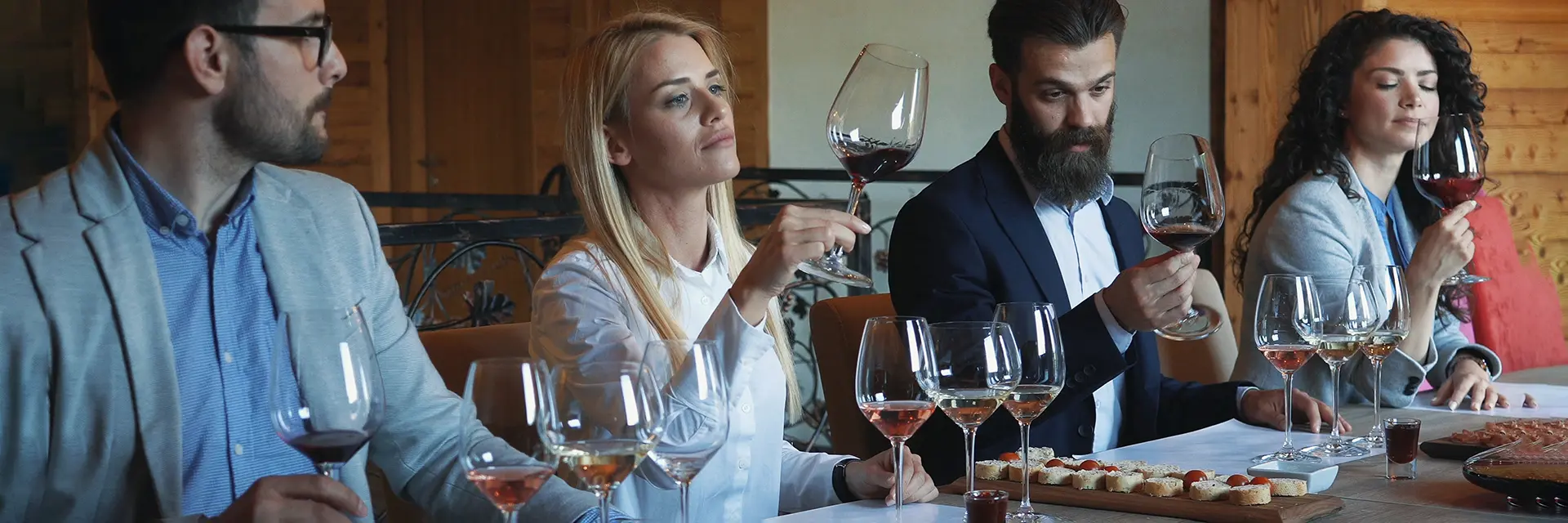 Foto av fire mennesker som sitter ved et bord og smaker på vin