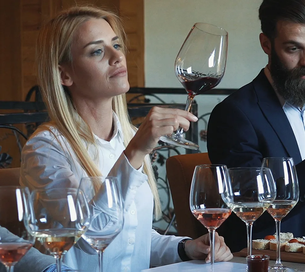 Foto av fire mennesker som sitter ved et bord og smaker på vin