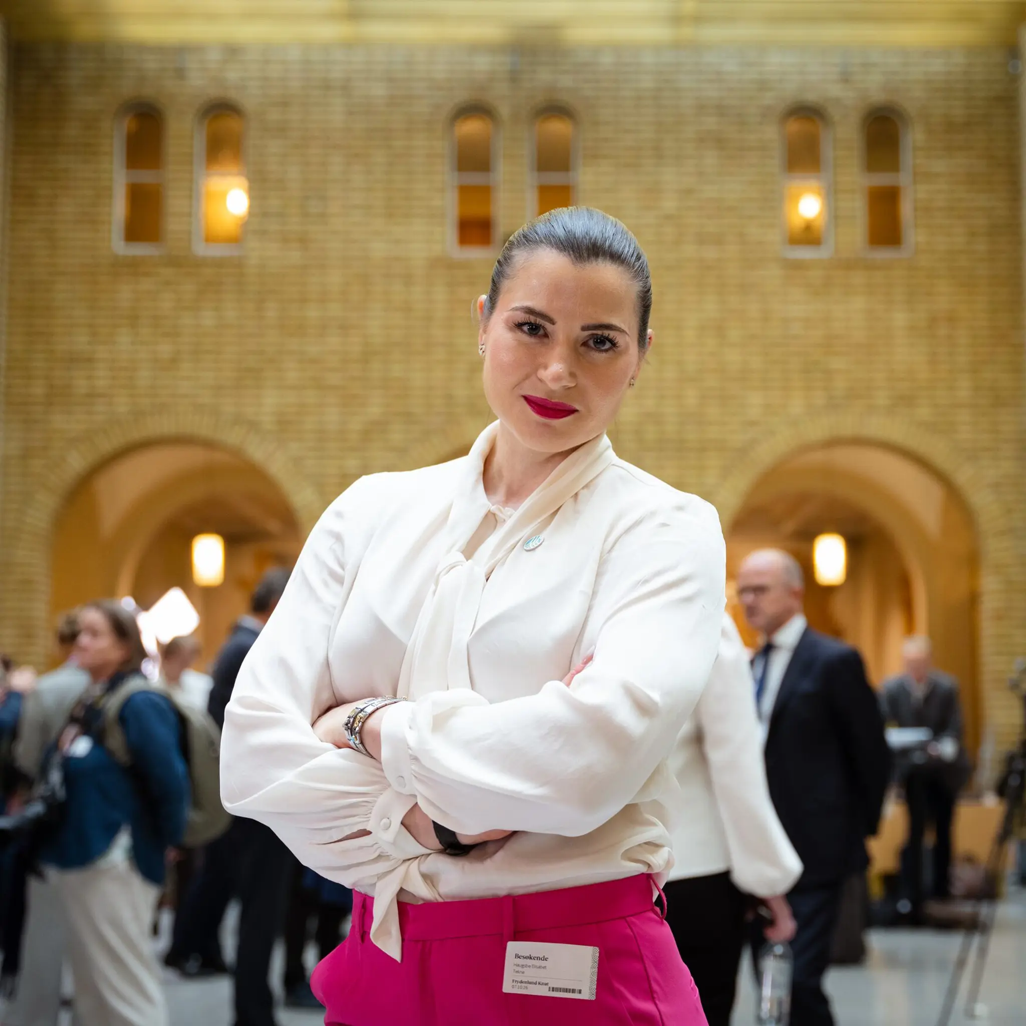 Elisabet Haugsbø med armene i kors i stortigets vandrehall, rosa bukser, hvit bluse