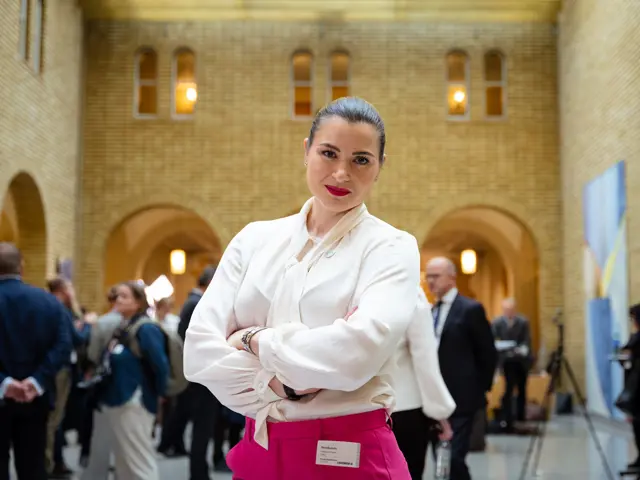 Elisabet Haugsbø med armene i kors i stortigets vandrehall, rosa bukser, hvit bluse