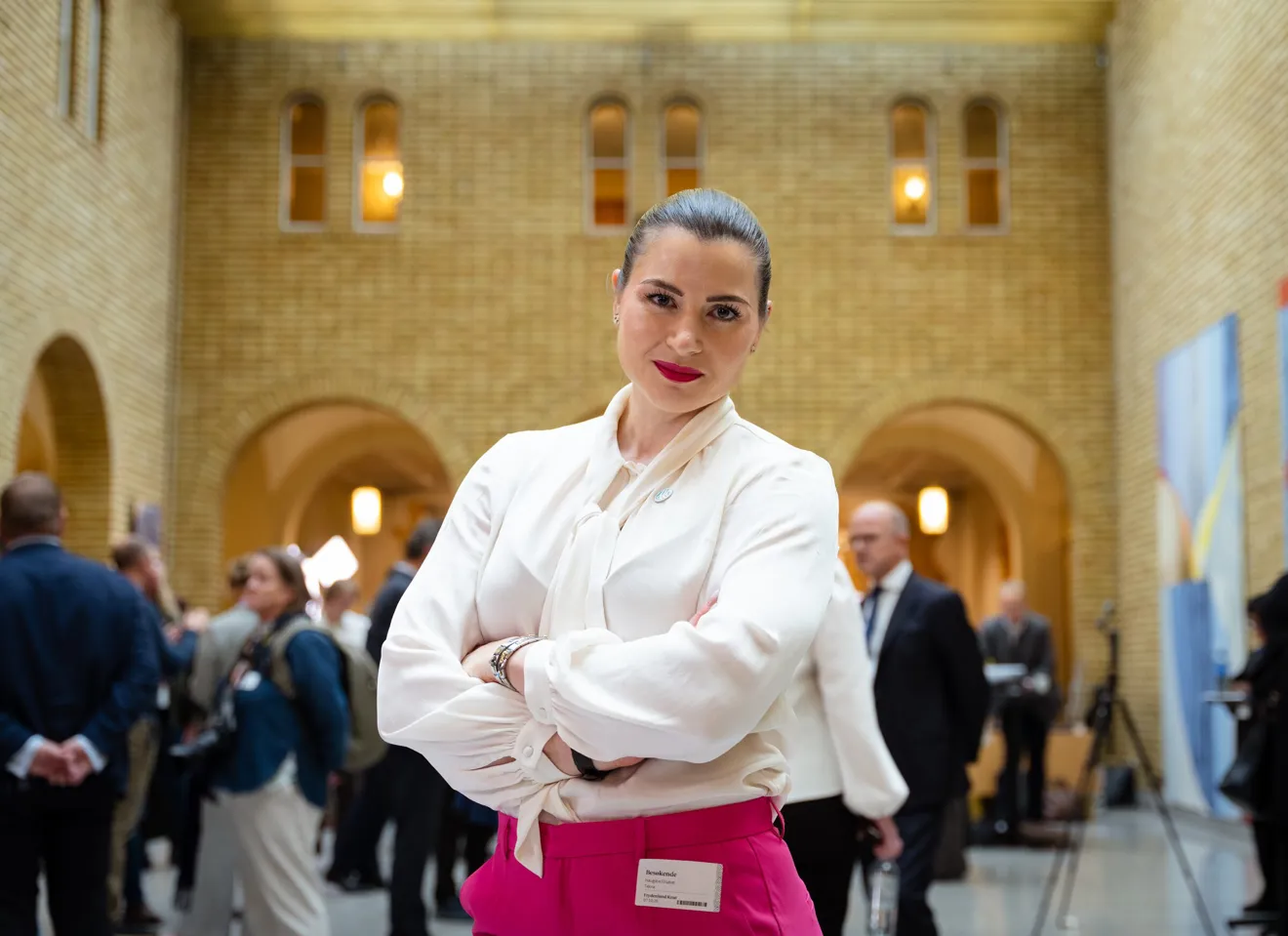 Elisabet Haugsbø med armene i kors i stortigets vandrehall, rosa bukser, hvit bluse