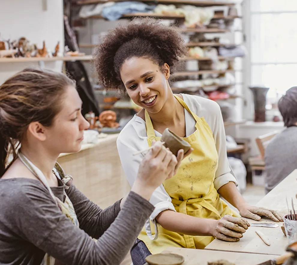 En jente som lager mønster i en keramikkgjenstand og en jente som ser på