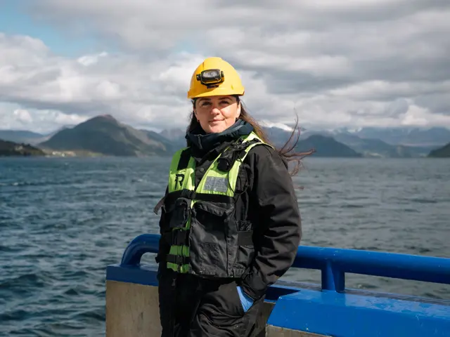 Kvinne med hjelm på oppdrettsanlegg