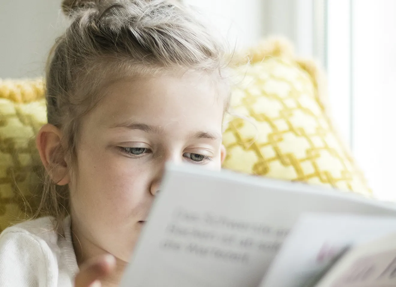 Illustrasjonsbilde av et barn, en jente, som sitter og leser en bok