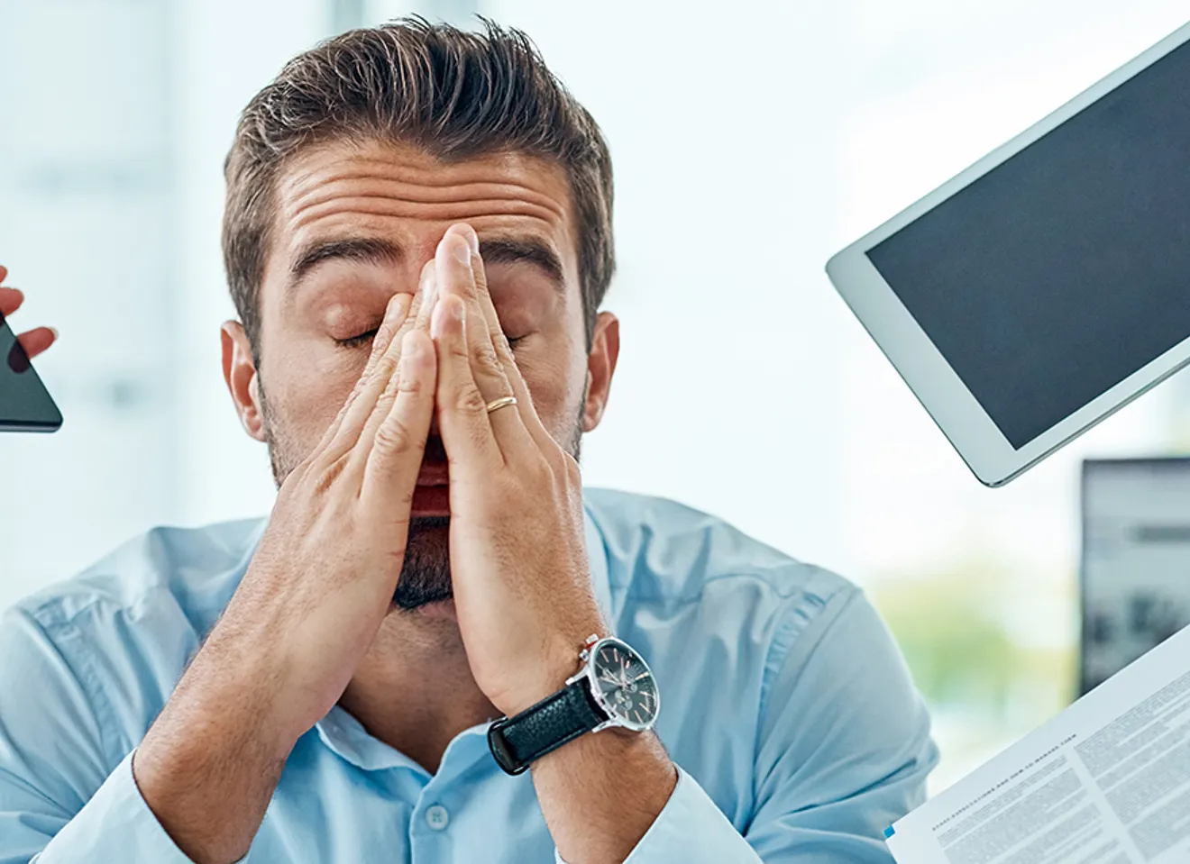 Mann som er fortvilet med mobiler og iPader rundt seg