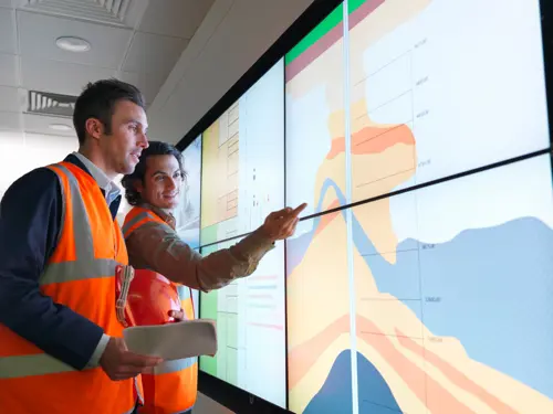 To arbeidere analyserer en graf på skjerm