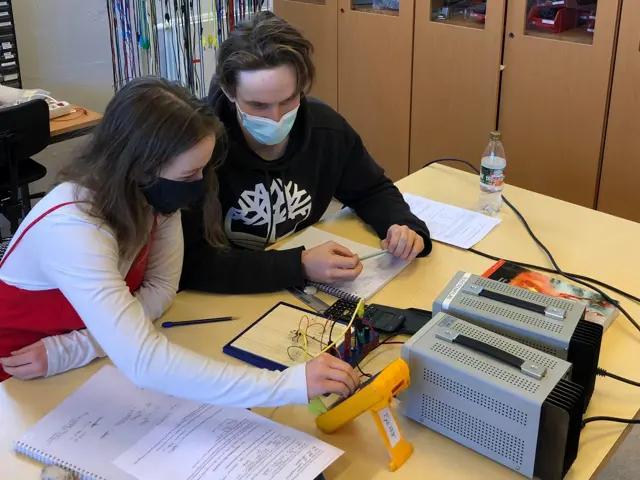 Leah Henriksen og Kristoffer Solheim Smith sitter ved et bord med elektrisk måleutstyr