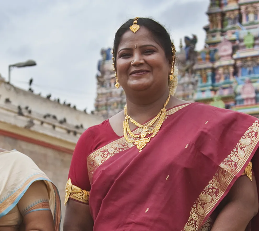 To smilende kvinner i sari foran templer i byen Madurai i India