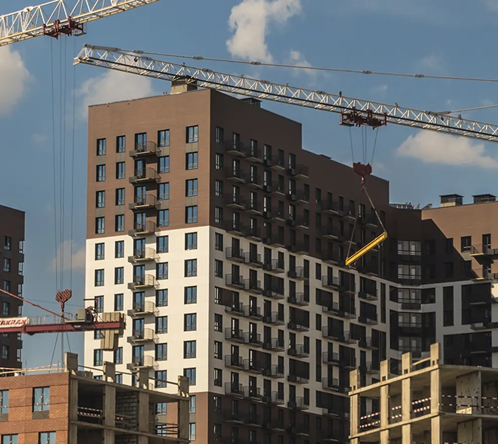 To heisekraner som holder på å bygge nye bygg