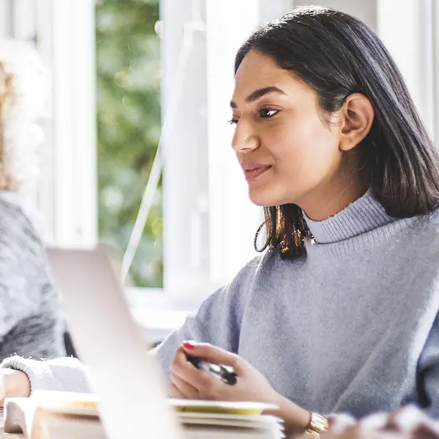 Jente med mørkt hår som ser på pc`en