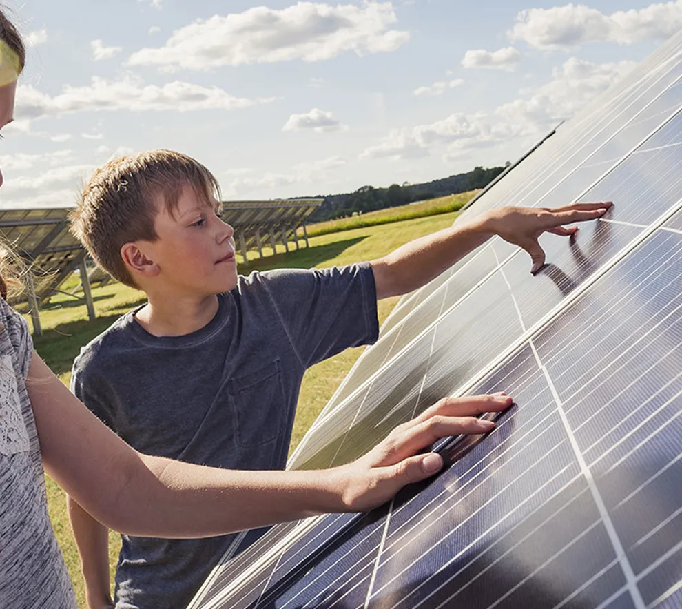 Barn ved solcellepaneler en sommerdag