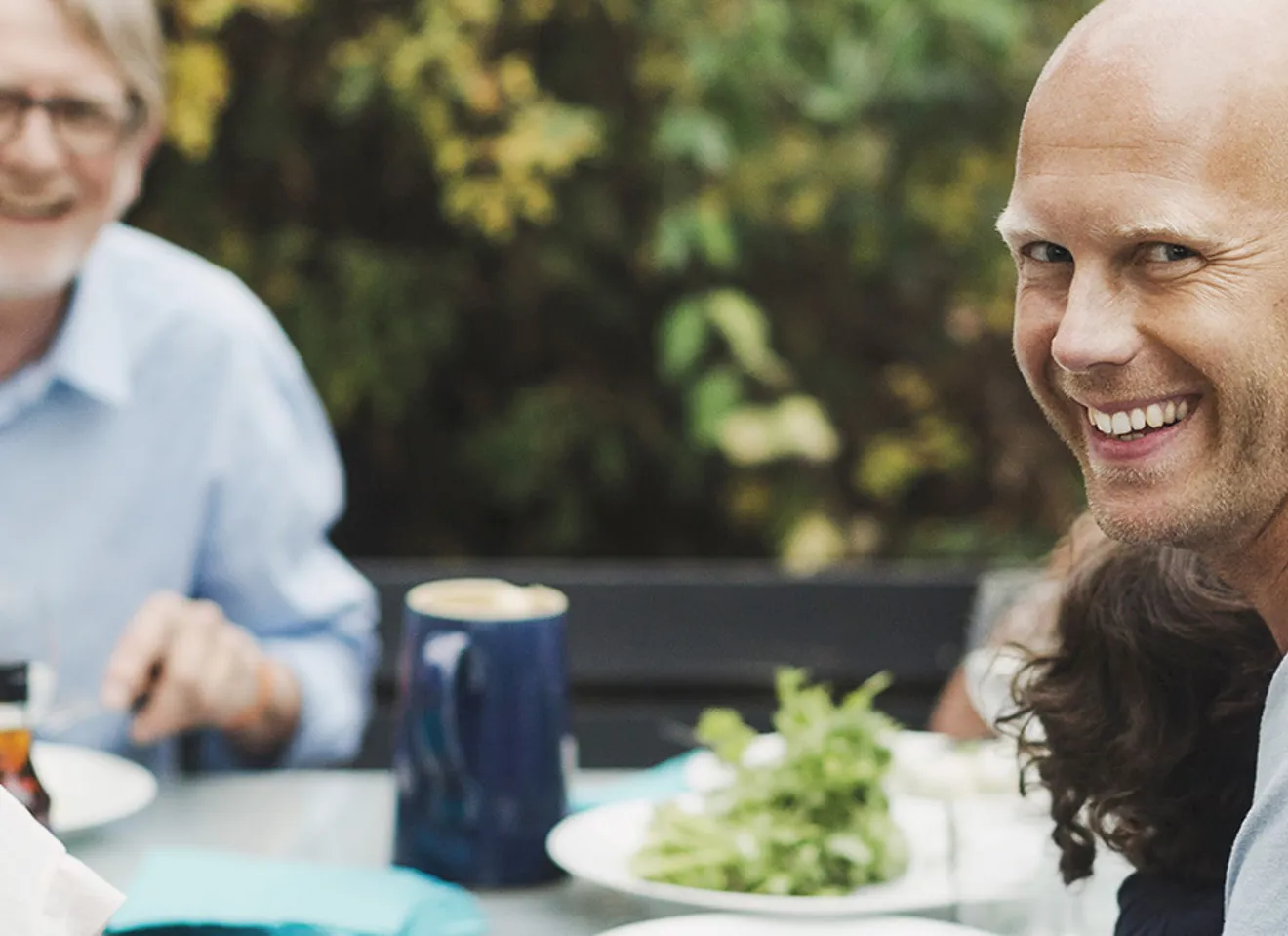 Familie samlet rundt et middagsbord ute på sommeren