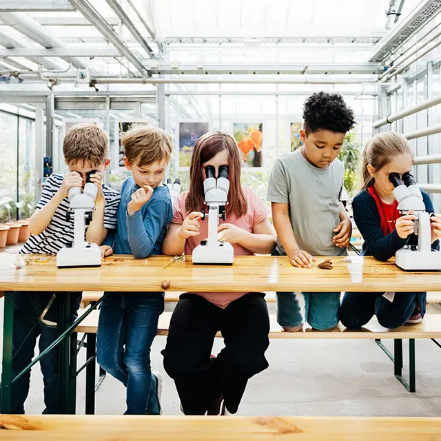 Fem barn som ser i mikroskop