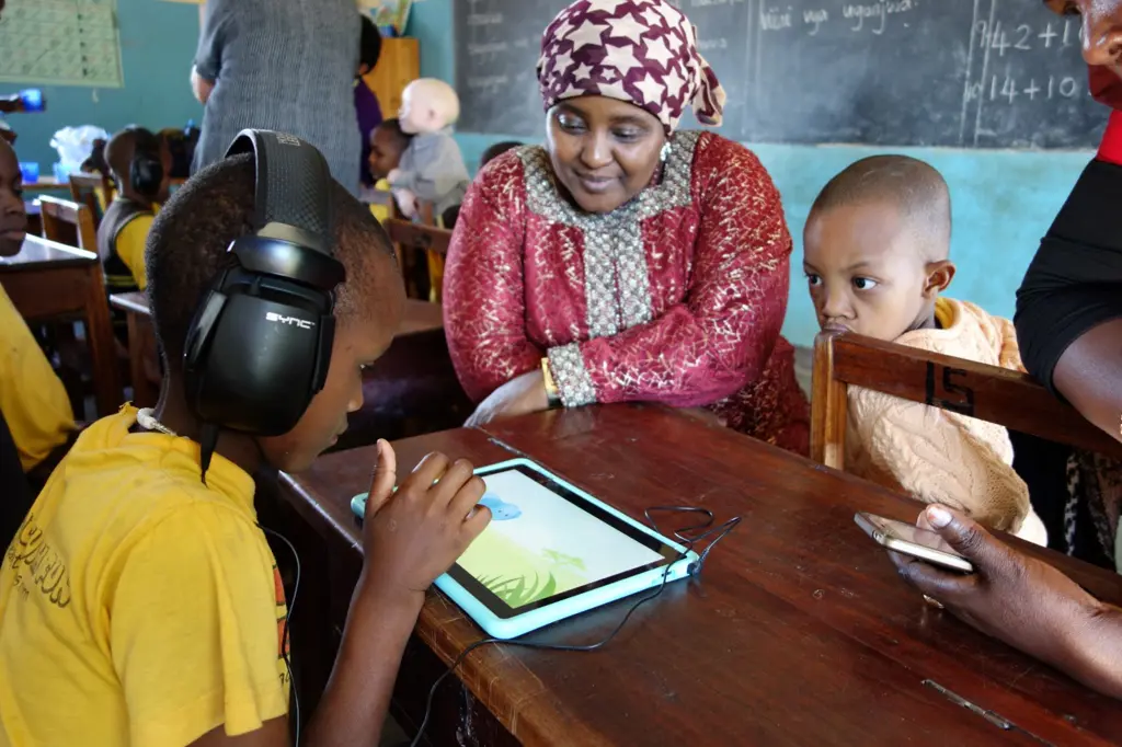 En afrikansk kvinne ved siden av to afrikanske barn som prøver ut app på en nettbrett