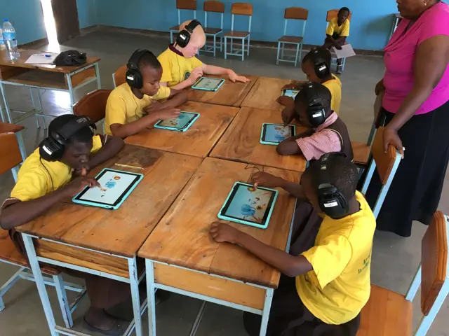 Flere barn som sitter ved et bord med hver sitt nettbrett