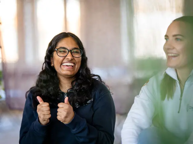 To glade unge kvinner - en med tomlene opp