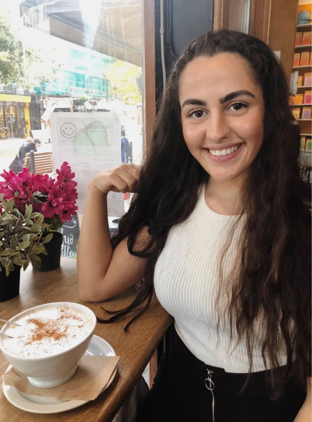 Foto av Lina som sitter på café og drikker kaffe